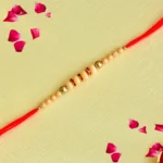 Classic Elegance Rakhi – RK-126 | Beige Beads with Gold Highlights on Red Thread
