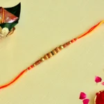 Festive Elegance Rakhi – RK-128 | Bright Orange Thread with Ornate Beads