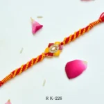 Sunlit Bloom Rakhi – RK-226 | Floral Rakhi with Yellow-Red Thread Work & Crystal Centerpiece