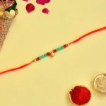 Golden Beaded Rakhi – RK-146 | Red & Green Elegance with Blessings